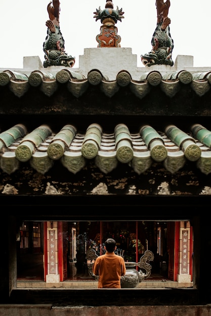 お香でお寺で祈る男の背面図