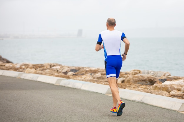 Free photo back view of man running on sea coast