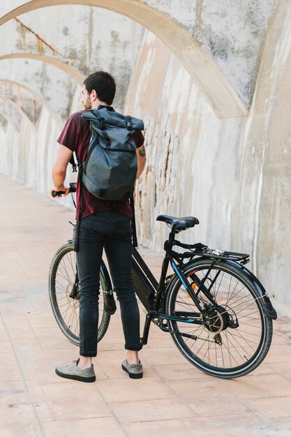 電動自転車の隣に立っている男の背面図