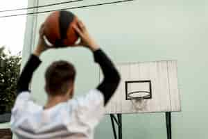 Free photo back view man throwing a basketball