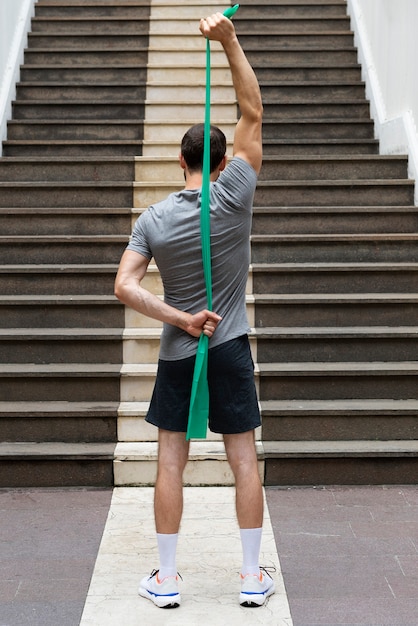 Back view man training with elastic band