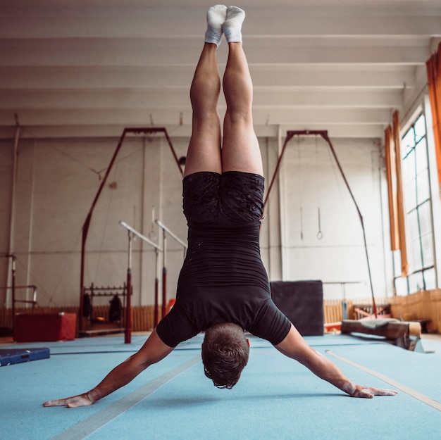 Free photo back view man training with parallel bars