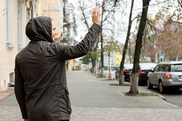 Вид сзади человека, идущего по улице и приветствующего