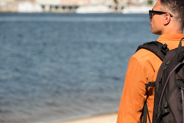 Vista posteriore dell'uomo con lo zaino in spiaggia