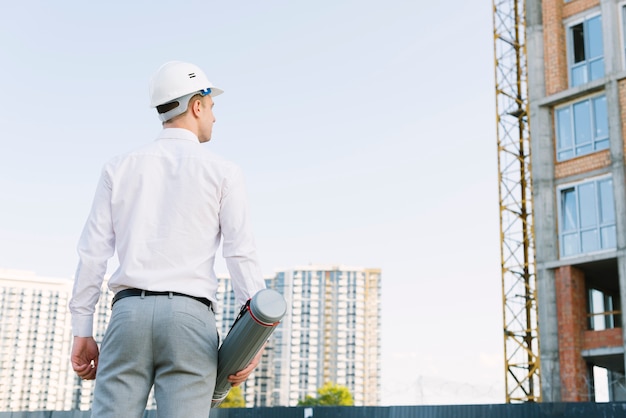 Back view man with safety helmet outdoors