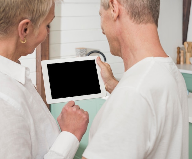 Foto gratuita vista posteriore uomo e donna in possesso di un tablet vuoto