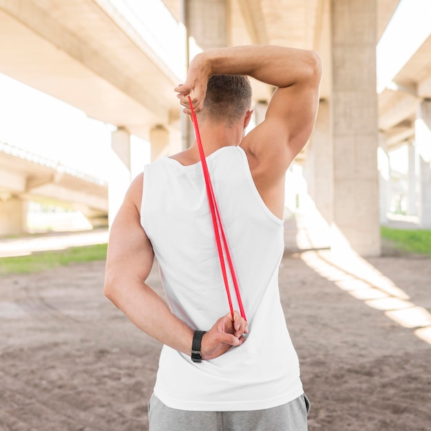 Free photo back view man working out with a red stretching band