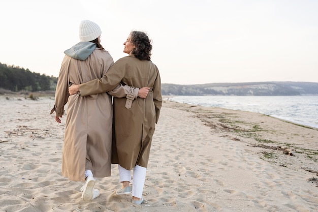 Back view of mother and daughter walking on the beach