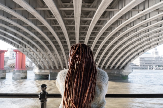 Бесплатное фото Вид сзади на афро-дреды на женщине, позирующей на улице под мостом