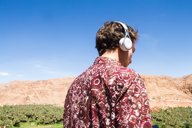 Бесплатное фото Вид сзади человека, слушающего музыку в оазисе