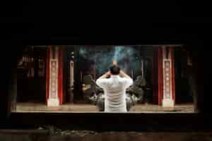 無料写真 燃える線香で寺院で祈る男の背面図