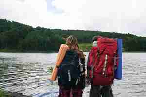 Бесплатное фото Вид сзади двух туристов с рюкзаками лицом к воде