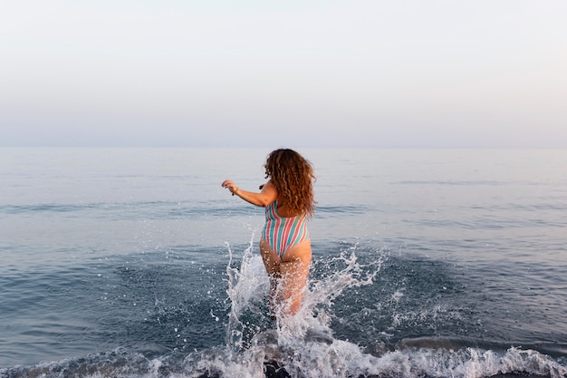 無料写真 水に行くビーチで女性の背面図