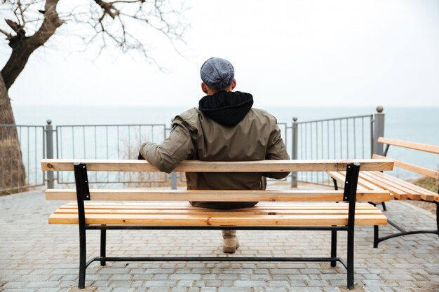 Back view picture of young african man on a bench