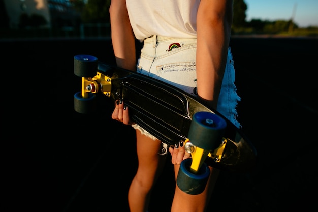 Free photo back view of a pretty girl with a skateboard in her hands.