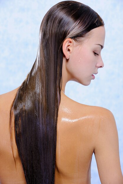 Back view of pretty young female with wet long hairs