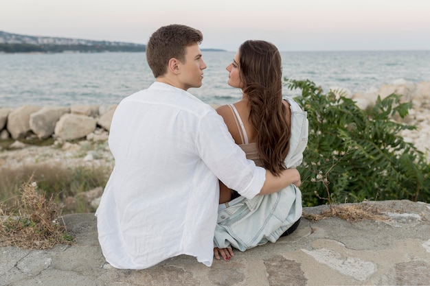 Back view of romantic couple holding each other by the ocean