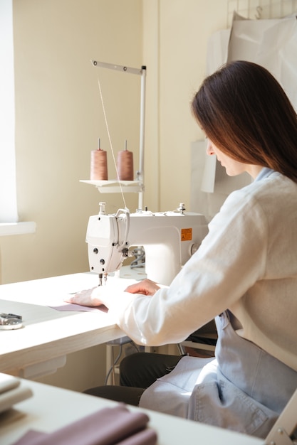 Back view of seamstress working with sewing machine