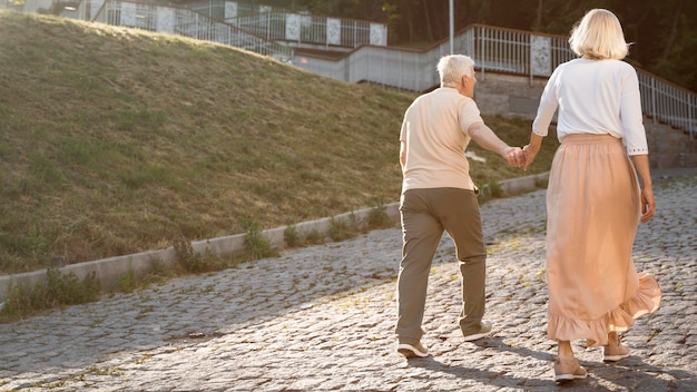 Back view of senior couple holding hands while out in the city