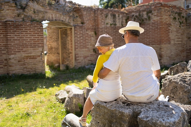 Back view senior couple sitting on rock