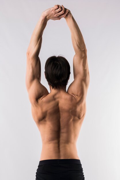 Back view of shirtless muscled man with arms up