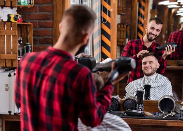 Free photo back view smiley barber using hairdryer