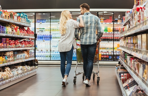 Free photo back view of a smiling couple walking with a trolley