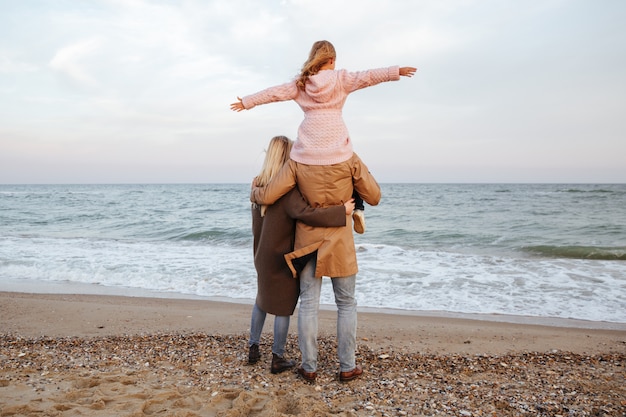 Back view of a smiling family with a little daughter