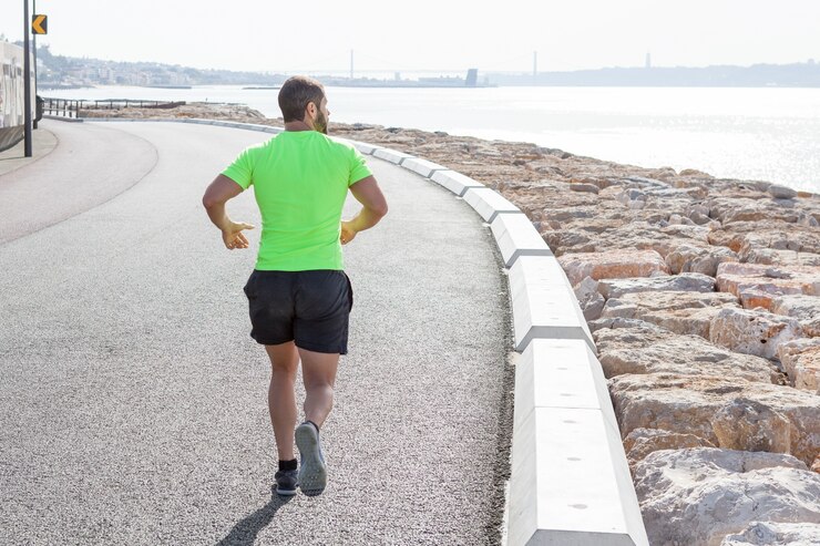 Free Photo back view of strong man running on road by sea