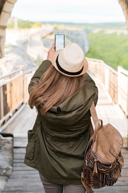 Back view stylish traveller taking pictures outdoors