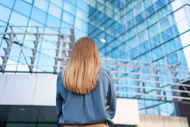 Free photo back view of successful manager looking at business building of modern city.