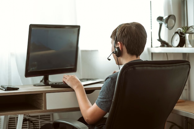 Back view teenage boy playing a game online