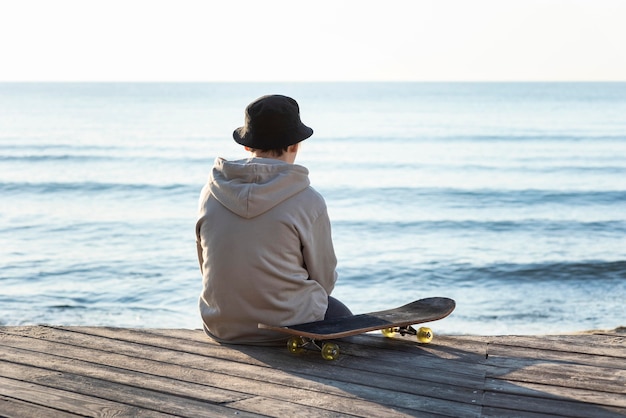 Free photo back view teenage boy with skateboard