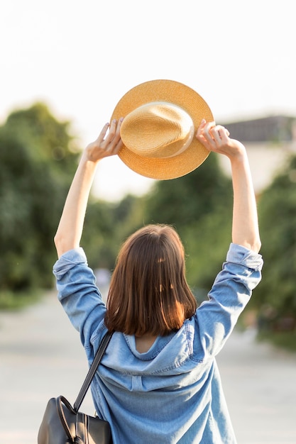 Back view traveller holding hat oudoors