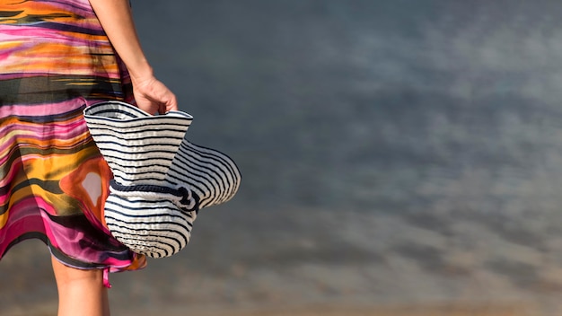 Back view of woman at the beach holding hat