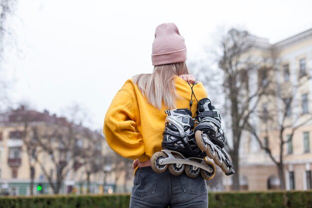 Back view of woman in beanie carrying roller blades