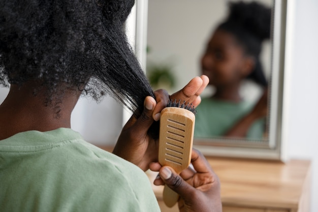 Foto gratuita capelli di spazzolatura della donna di vista posteriore