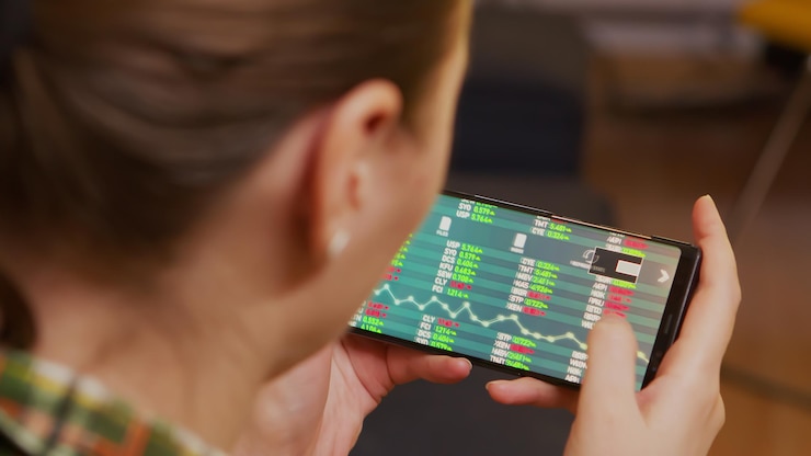 Free Photo back view of woman checking stock trading using smartphone.