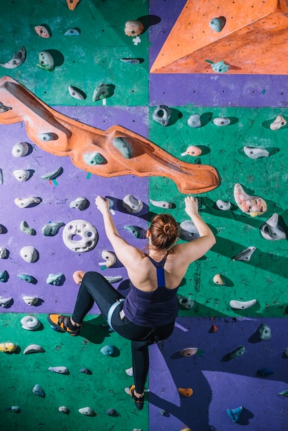 Back view woman climbing wall