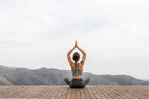 Foto gratuita vista posteriore della donna che fa yoga all'aperto