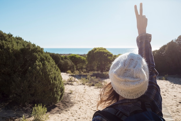 Free photo back view woman gesturing peace in nature