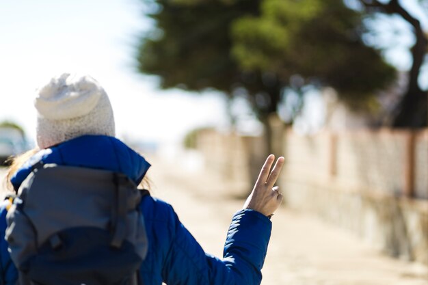 Back view woman gesturing peace