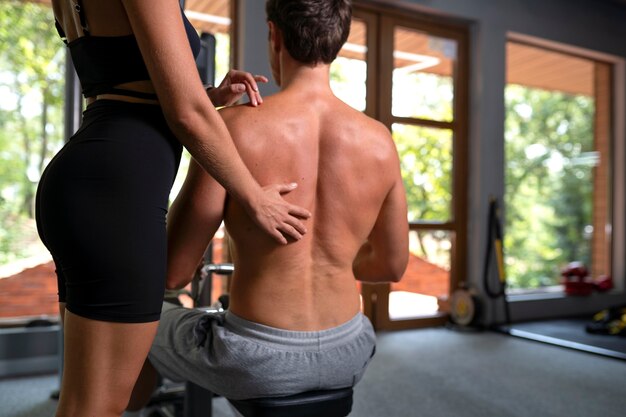 Back view woman helping man workout