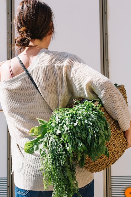 Free photo back view woman holding basket with greenery