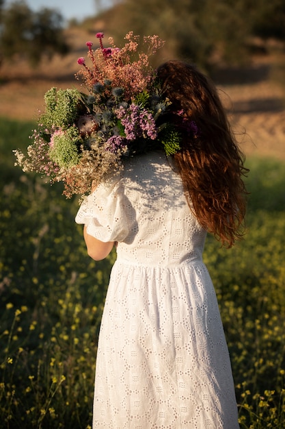 Free photo back view woman holding beautiful flowers bouquet