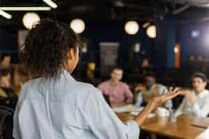 Free photo back view of woman holding a meeting at work with colleagues