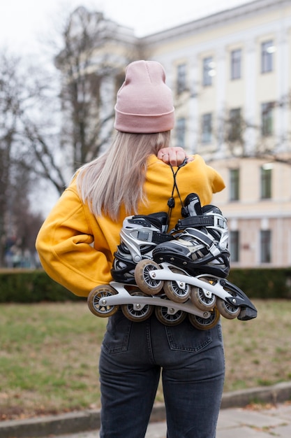 Free photo back view of woman holding roller blades