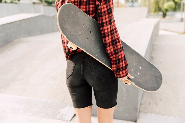 Back view of woman holding skateboard