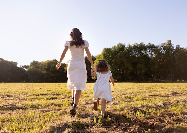 Free photo back view woman and kid holding hands