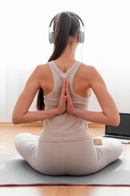 無料写真 ヘッドフォンで自宅で瞑想する女性の背面図